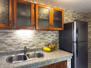 Costa Rican kitchen with granite countertop, wooden cabinets, and stainless steel fridge.