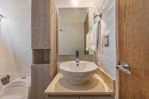 Contemporary bathroom with a round sink, mirror, and wooden cabinetry.