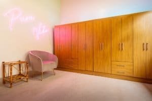 Spacious closet with wooden cabinets and pink neon sign in Dominical.