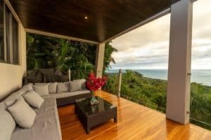 Balcony of a modern jungle home with ocean view and lush greenery.