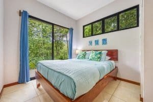 Bright bedroom with large windows overlooking lush jungle in Costa Rica.
