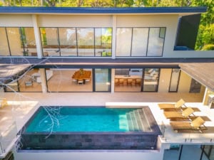 Modern tropical home with infinity pool, ocean view, and outdoor lounge area.