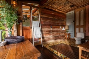 Cozy bathroom with wooden walls, toilet, and decorative rug in Dominical.