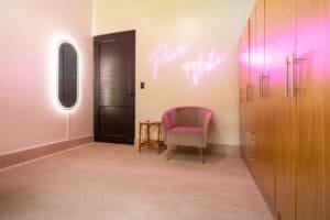 Stylish interior with neon sign, pink chair, and wooden cabinets in Dominical.