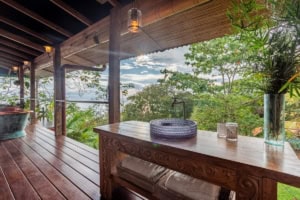 Balcony with ocean view, lush greenery, and wooden decor in Dominical.
