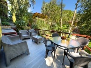 Relaxing outdoor terrace with seating and lush tropical garden view.
