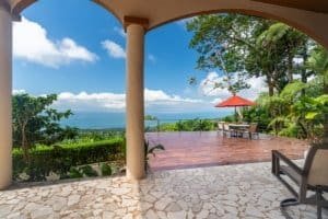 Mediterranean-inspired villa with ocean view, outdoor patio, and lush greenery.