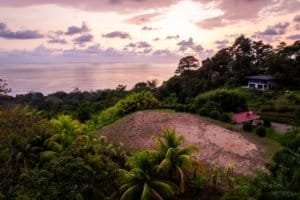 Scenic view of coastal estate with ocean, lush greenery, and sunset sky.