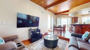 Bright living room with TV, wooden ceiling, and ocean view in Dominical.