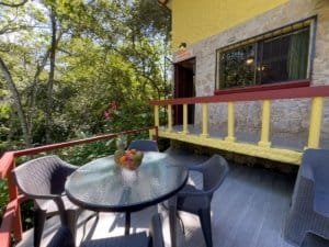 Outdoor patio with table and chairs in lush green setting.