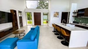 Spacious living room with blue sofa, large windows, and mountain view in Dominical.
