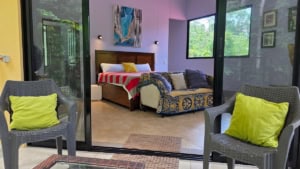 Interior of a bedroom with pool view, colorful decor, and outdoor seating.