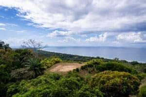 Scenic view of the ocean, lush greenery, and cloudy sky in Dominical, Costa Rica.