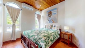 Bedroom with ocean and mountain view, tropical decor, and wooden ceiling.