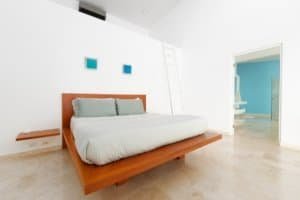 Contemporary bedroom with white walls, wooden bed, and blue accents.