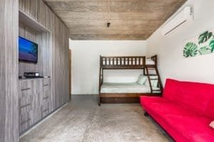 Interior of a Costa Rican studio with bunk bed, red sofa, and TV.
