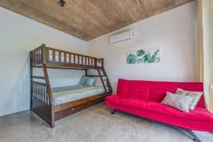 Interior of a Costa Rican home with bunk bed and red sofa, modern decor.
