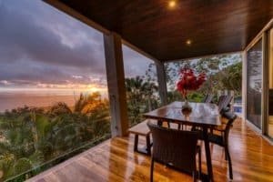 Balcony with ocean view, tropical trees, and sunset in Dominical, Costa Rica.