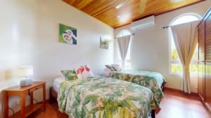 Bright bedroom with twin beds, tropical decor, and ocean view windows.
