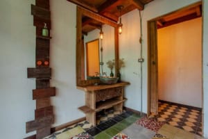 Rustic bathroom with wooden vanity, hanging lights, and colorful tiled floor.