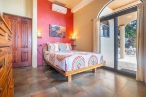 Bedroom with colorful bedding, wooden furniture, and sliding glass door to patio.