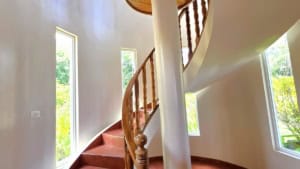 Elegant spiral staircase inside a Spanish Colonial-style home with mountain views.