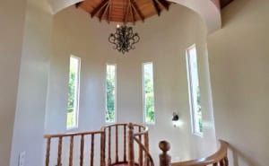 Elegant interior with curved walls, wooden staircase, and chandelier.