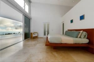 Modern bedroom with ocean view, sliding glass doors, and minimalist decor.