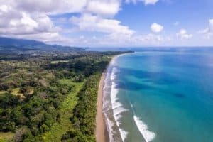 Aerial view of Dominical beach with lush greenery and ocean waves.