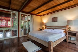 Bedroom with wooden furniture, large bed, and balcony access in Costa Rica.
