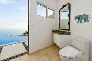 Contemporary bathroom with ocean view, minimalist decor, and unique wall art in Costa Rica.
