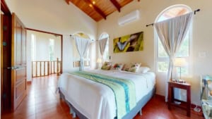 Bright bedroom with large windows, white curtains, and mountain scenery.