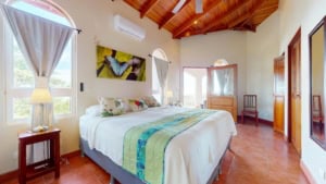 Bright bedroom with large windows, mountain view, and wooden ceiling.