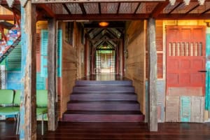 Interior view of a rustic, elevated home entrance with wooden stairs and colorful decor.