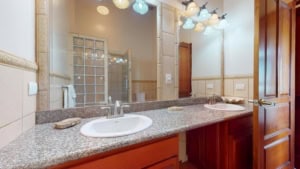 Bathroom with dual sinks, granite countertop, and decorative lighting.