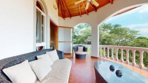 Balcony view of a Spanish Colonial-style home with ocean and mountain scenery.