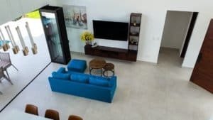 Spacious living room with blue sofa, TV, and panoramic ocean view in Dominical.