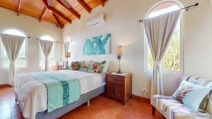 Bright bedroom with large windows, tropical decor, and mountain scenery.