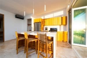 Bright kitchen with wooden cabinets and ocean view from sliding door.