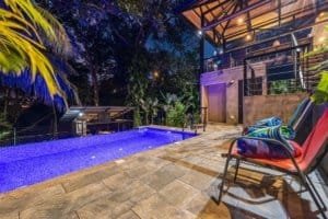 Night view of a luxury pool with lounge chairs and tropical trees in Dominical.