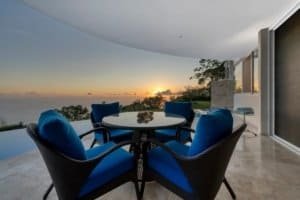 Outdoor dining area with ocean sunset view and jungle backdrop.