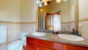 Bathroom with dual sinks, granite countertop, and tropical decor in Dominical.