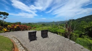 Two chairs on patio overlooking lush green hills and ocean in Dominical.