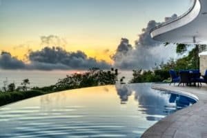 Infinity pool overlooking jungle and ocean at sunset in Dominical.