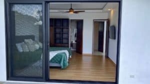 Modern bedroom with mountain view, wooden floors, and sliding glass door.