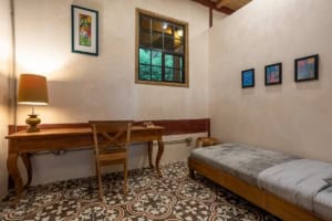 Interior of a bedroom with a wooden desk, window, and single bed in Dominical.