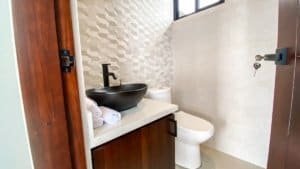 Contemporary bathroom with black vessel sink and textured wall tiles.