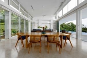 Bright dining area with large windows overlooking lush greenery and ocean.
