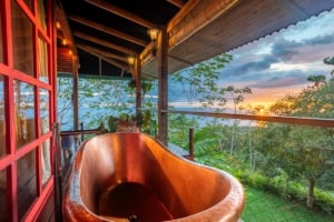 Balcony with ocean view and wooden bathtub at sunset in Dominical.