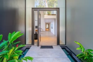 Contemporary entrance to a luxury tropical home with lush greenery.